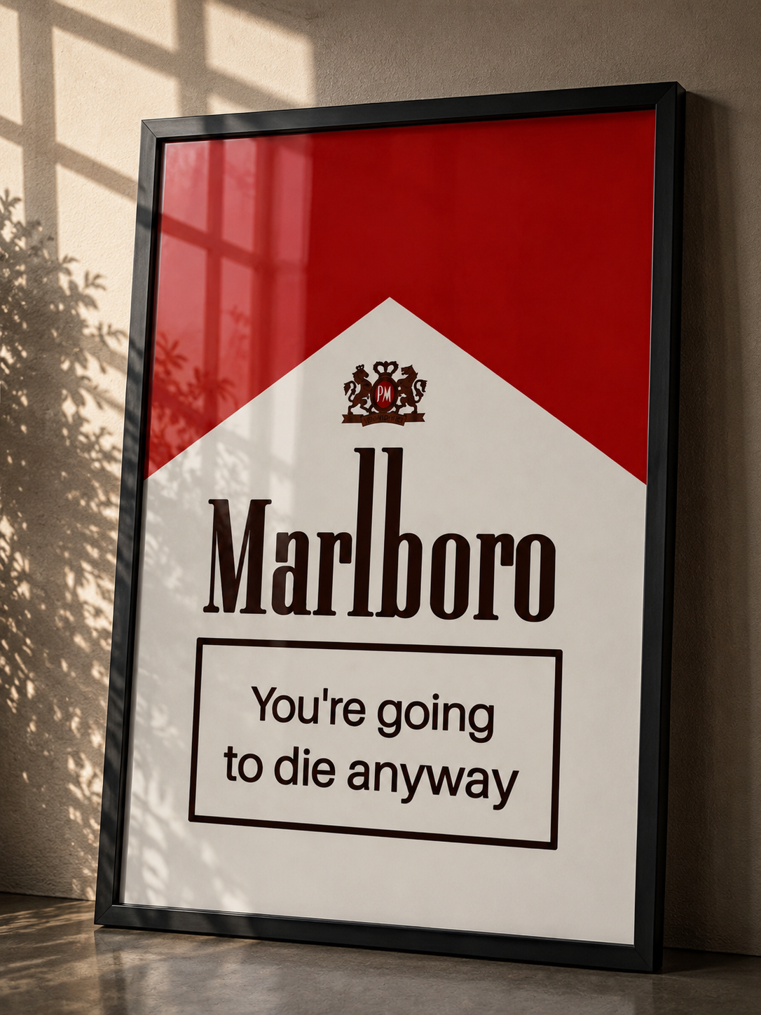 A framed Marlboro cigarette pack style wall art print leaning against a wall in a real interior setting. The print has a red and white panel with the Marlboro logo and the text 'You're going to die anyway' in a black frame.