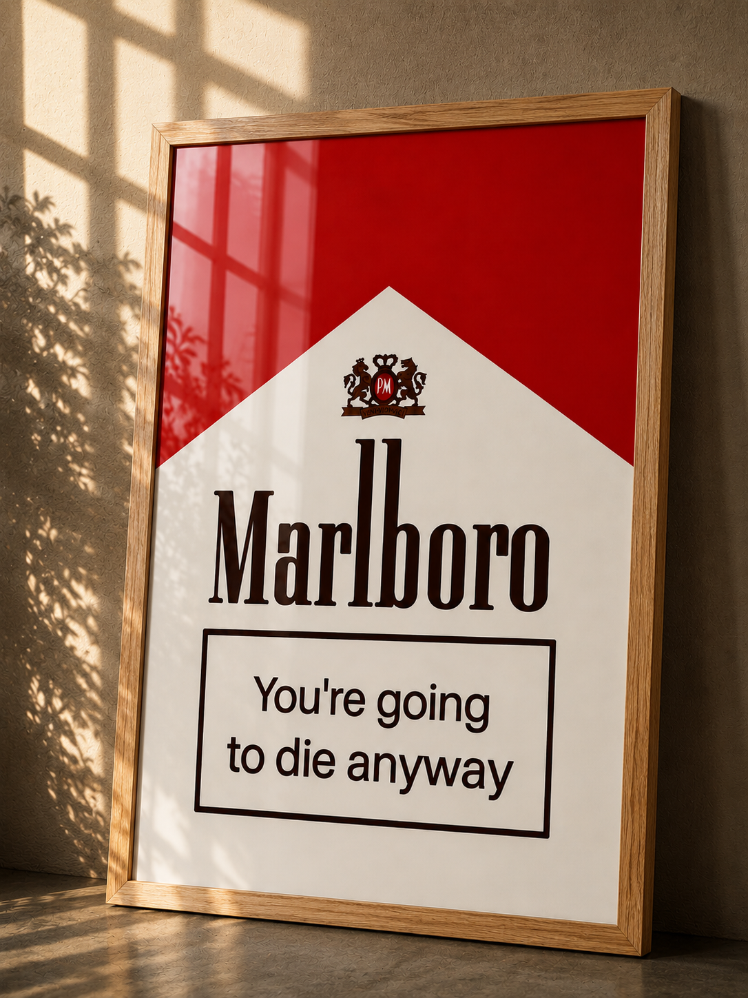 A framed Marlboro warning sign print leaning against a wall, with a light wood frame, red and white design, and the text 'You're going to die anyway' in a real interior setting with sunlight and shadows.